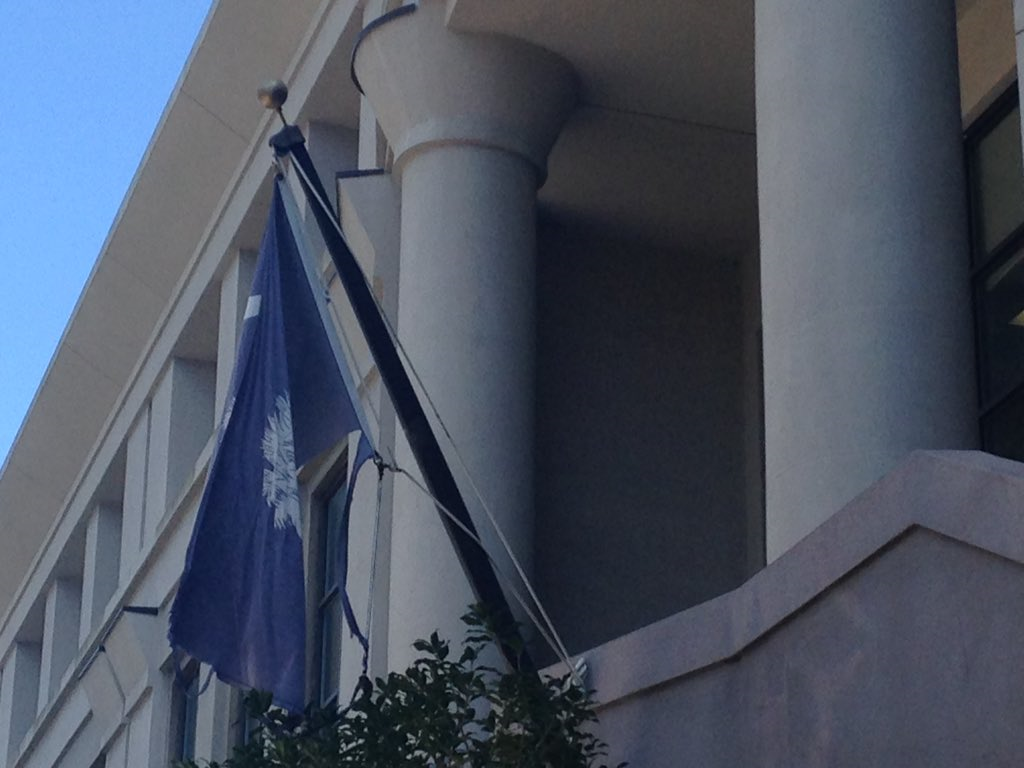 A tattered South Carolina flag hangs from a flagpole in front of the Charleston County School District office