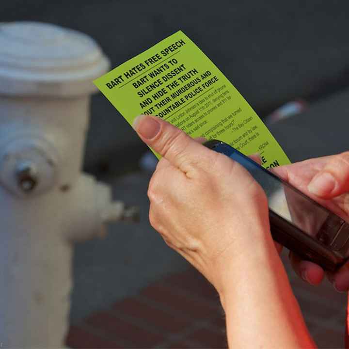 Person holding cell phone and flyer